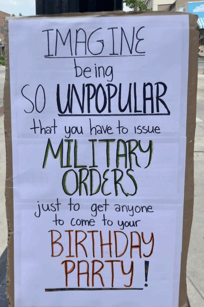 A sign with the words, "Imagine being so unpopular that you have to issue military orders just to get anyone to come to your birthday party!"